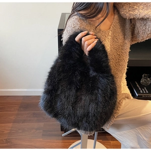 Close-up of fluffy black faux fur handbag texture with a cozy winter aesthetic