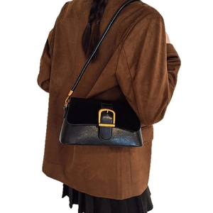 Retro black leather and suede shoulder bag with gold buckle worn by model on blazer