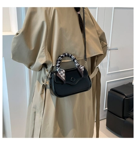 Detail of black glossy square handbag with checkered heart silk scarf on the handle