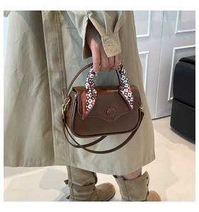 Detail of dark brown leather handbag with heart-print silk scarf handle and crossbody strap