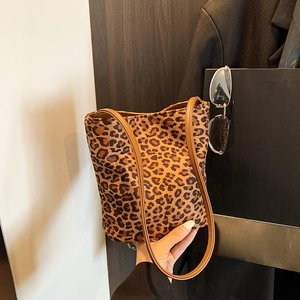 Fashionable leopard print bucket bag with brown leather straps shown in hand