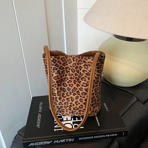 Fashionable leopard print bucket bag with brown leather straps on a designer book
