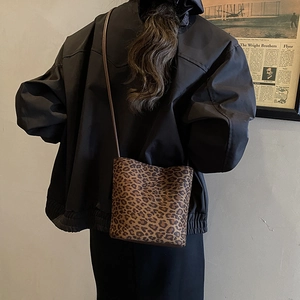 Fashionable leopard print bucket bag with long shoulder strap worn by a model