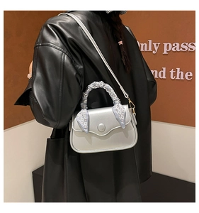 Detailed side view of silver crossbody bag with decorative silk scarf on the top handle