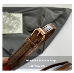 Detail of adjustable brown leather shoulder strap with gold buckle and fine stitching