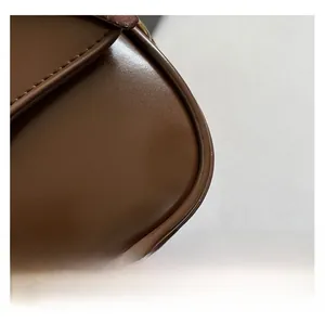 Macro detail of dark brown leather handbag showing smooth finish and curved edges