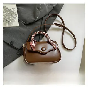 Detail of brown leather saddle bag with silk scarf handle on a grey suit background