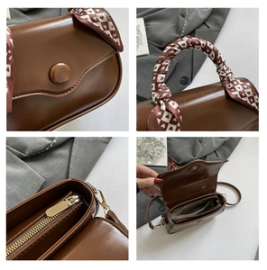 Detail view of brown square handbag featuring a heart pattern silk scarf on handle