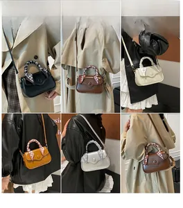 Detail of square handbag with silk scarf wrapped handle and magnetic snap closure
