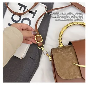 Detail showing the adjustable brown shoulder strap with golden metal buckle on handbag
