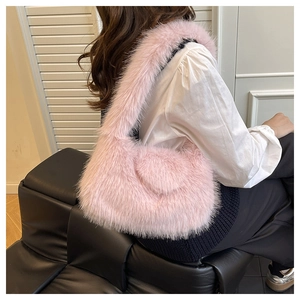 Detailed view of pink plush handbag featuring heart applique and fuzzy strap on shoulder