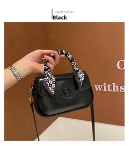 Detail of black glossy handbag featuring a checkered heart scarf wrap on the handle
