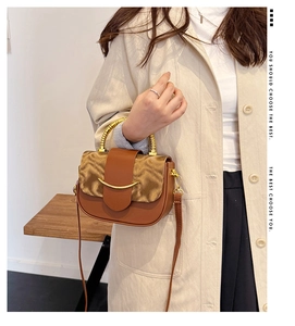 Close-up of brown leather saddle bag with gold bamboo handle and metallic flip cover