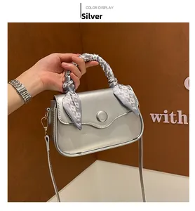 Detail of silver square handbag with wavy flap and silk scarf wrapped on handle