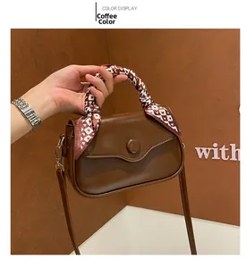 Detail of coffee brown square bag with heart print silk scarf handle and matte leather finish