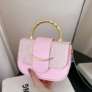Close-up of pink patchwork handbag with golden bamboo-shaped handle and metal clasp