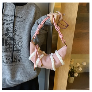 Dettaglio borsa a mezzaluna in camoscio rosa con finiture in pelliccia e tracolla