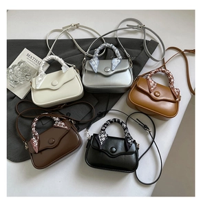 Flat lay of small crossbody bags in five colors with decorative silk scarf handles
