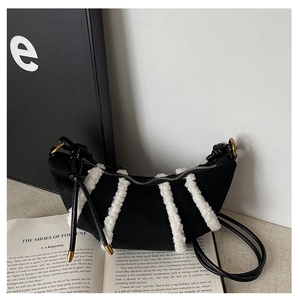 Dettaglio borsa hobo con texture nera satinata e strisce verticali in pile bianco