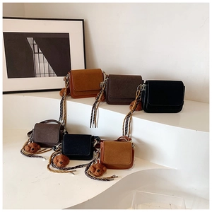Three-color minimalist square bags with woven straps and plush bear charms on display
