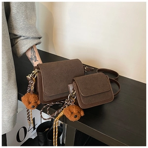Detail view of dark brown crossbody bags with suede patchwork and plush bear pendant