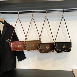 Detail of retro underarm bags with gold chain straps in burgundy, green, brown, and black