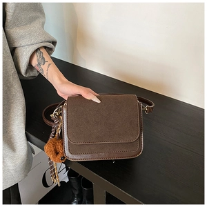 Detail of vintage brown square crossbody bag featuring mixed textures and a cute bear charm