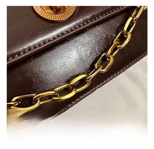 Close-up of brown leather bag featuring refined golden chain and metallic lock detail