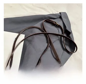 Detail of adjustable thin brown leather shoulder strap with golden metal buckle