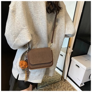 Detail of brown matte square bag with matching strap and cute teddy dog plush charm