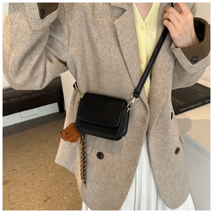 Detailed close-up of a black mini square crossbody bag with a cute plush bear charm