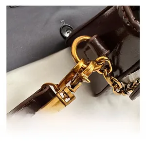 Close-up of vintage golden hook and thick metal chain on brown oily leather bag