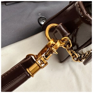Close-up of glossy dark brown leather bag with golden D-rings and fine stitching details