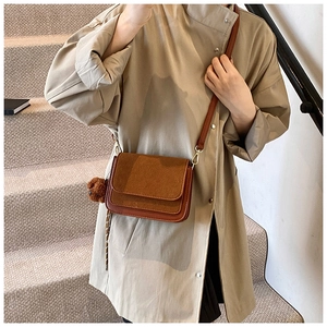 Brown leather crossbody bag with cute teddy bear charm on beige trench coat outfit