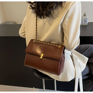Dettaglio di una borsa a catena marrone vintage su un blazer beige per uno stile ufficio
