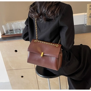 Close-up of brown faux leather handbag featuring a minimalist gold square metal buckle clasp