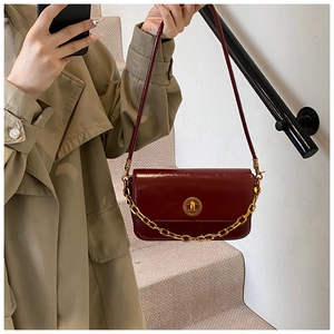 Close-up of vintage burgundy square bag with gold metal chain and rotary clasp