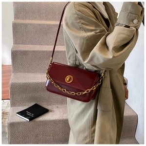 Detail view of burgundy leather small square bag with golden chain and twist lock clasp