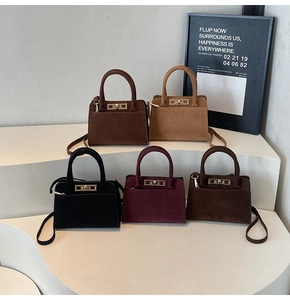 Close-up of matte suede handbags showing gold metal twist locks and elegant handle details