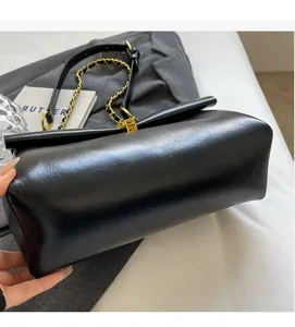 Dettaglio borsa a spalla in pelle nera opaca con tracolla a catena e fibbia dorata