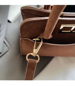Close-up of golden hardware connectors and textured matte brown leather on a handbag