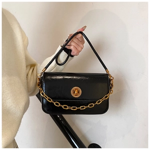 Detail of glossy black patent leather bag with chunky gold chain and metallic twist lock