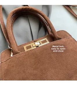 Detail of vintage caramel suede handbag showing gold metal hardware buckle and texture