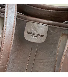 Dettaglio delle cuciture interne e del logo in pelle goffrata sulla borsa tote marrone