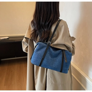 Detail of blue denim shoulder bag with black leather strap and silver metal buckle