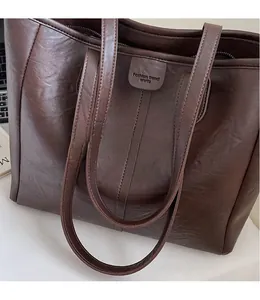 Dettaglio della borsa tote marrone scuro con texture in pelle e logo Fashion trend
