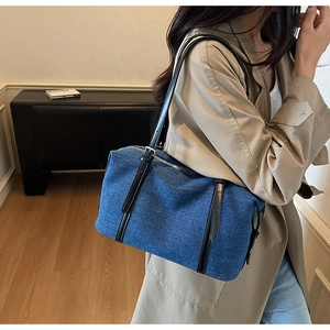 Denim shoulder bag with black leather strap shown in a stylish lifestyle interior setting