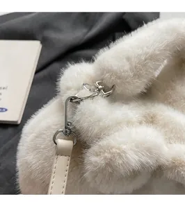 Detail of silver metal clasp and soft white plush texture on a stylish bucket bag