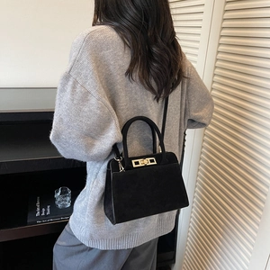Detailed view of the vintage matte black handbag with a metal twist lock on a model