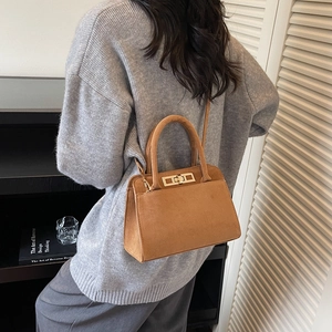 Detailed view of brown matte suede handbag featuring elegant gold twist lock closure